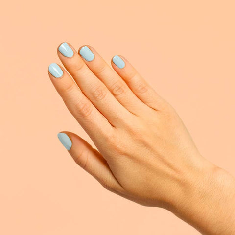Hand with light blue nail polish on a peach background