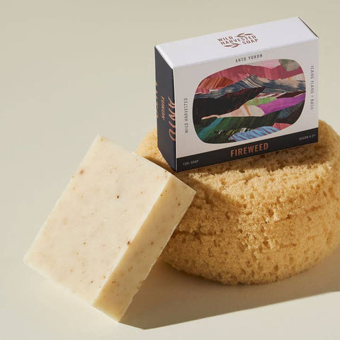 Bar of soap, sponge, and box labeled 'Wild Harvested Soap' on a beige background