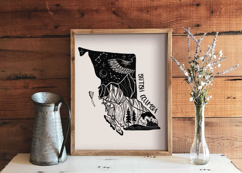 Framed black and white illustration of British Columbia on a wooden wall with decorative elements.