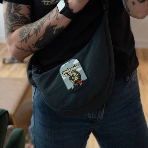 Person wearing a black bag with a colorful patch on a wooden floor.