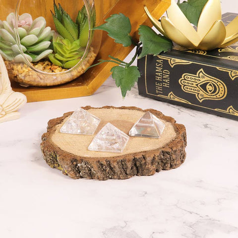 Crystal pyramids on a wooden slice with decorative items in the background