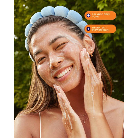 Woman applying a skincare product with text indicating benefits on a green outdoor background
