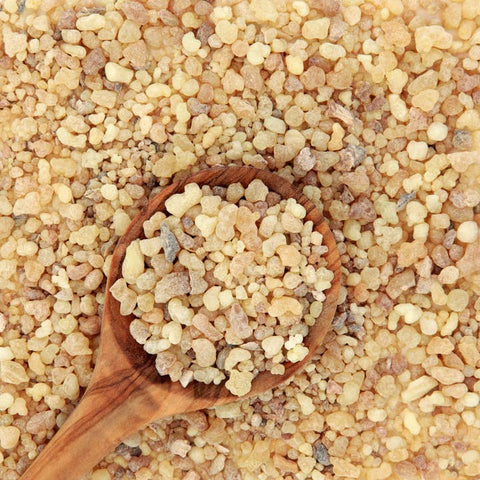 Wooden spoon filled with resinous frankincense substance on a bed of similar material