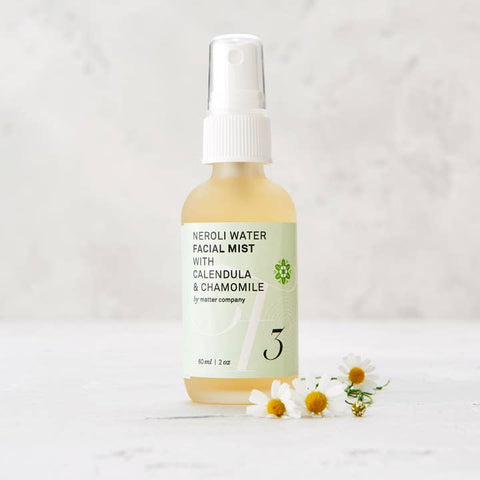Facial mist bottle with flowers on a light background