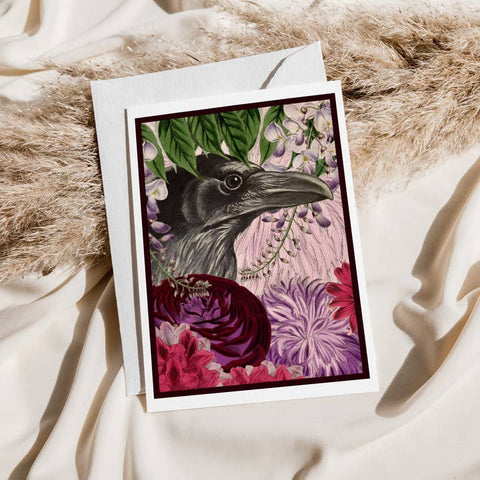 Greeting card with a crow and floral design on a textured surface
