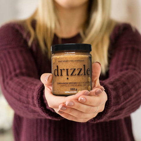 Person holding a jar of 'drizzle' cinnamon spiced honey