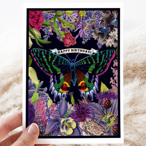 Greeting card with a colorful butterfly and floral design on a black background, held by a hand.