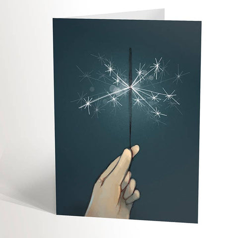 Greeting card with a hand holding a lit sparkler against a dark background