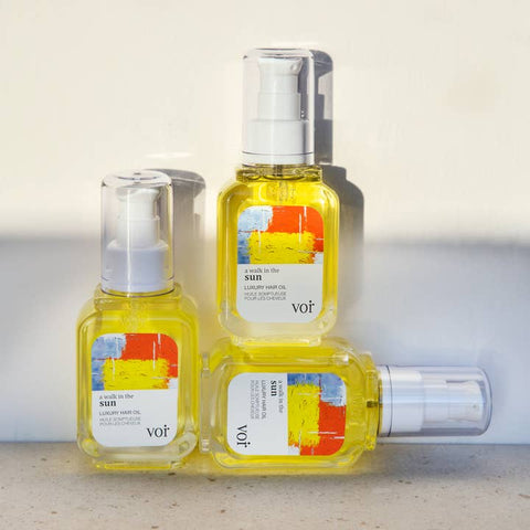 Three bottles of 'voir' hair oil with colorful labels on a light background