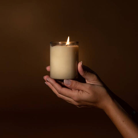 Hand holding a lit candle against a dark background