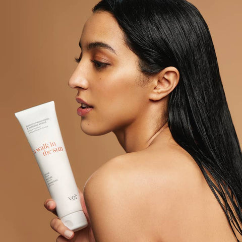 Woman holding a Voir haircare product with a brown background