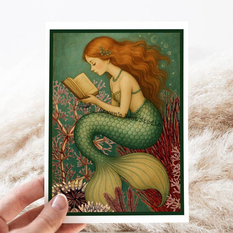 Mermaid reading a book in an underwater setting, held against a white background.