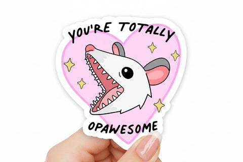 Sticker with a possum design and text held by a hand against a colorful background