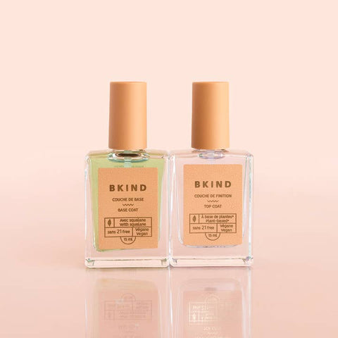 Two bottles of BKIND nail polish on a light pink background
