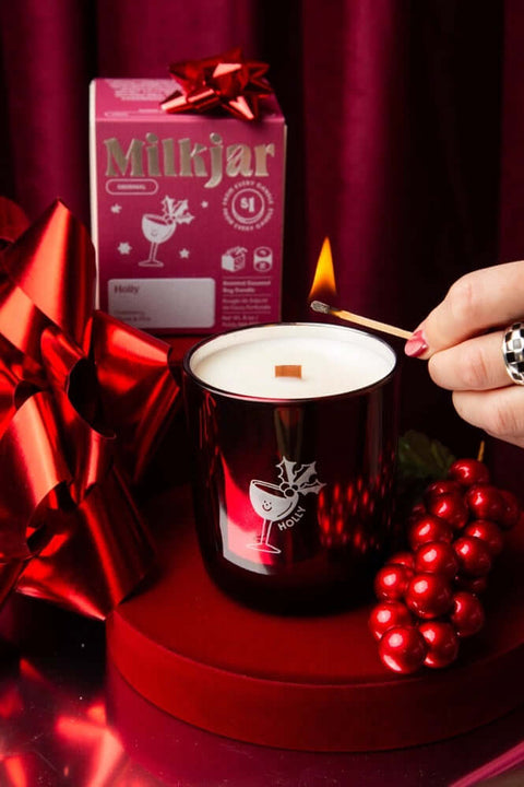 milk jar holly candle being lit by a match
