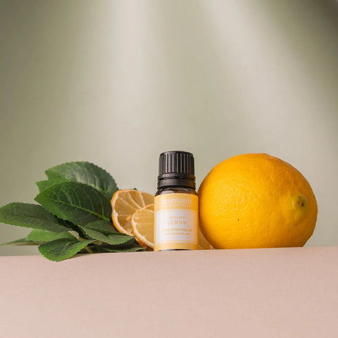 Lemon essential oil bottle with lemons and leaves on a neutral background